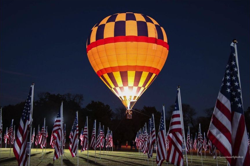 An illuminated balloon above the field of flags